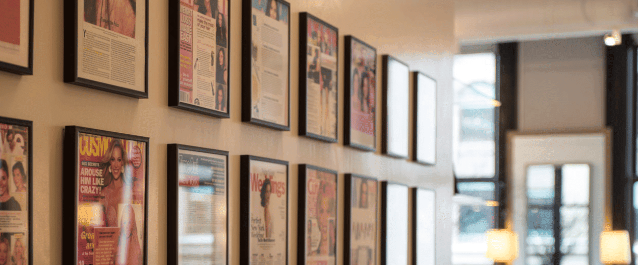 Wall decorated with framed magazine articles, creating a vibrant and artistic display.