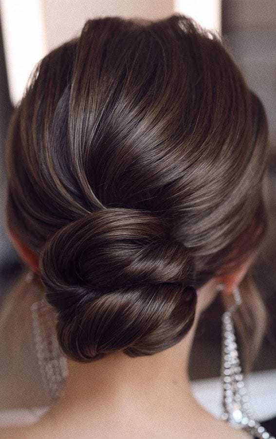 Elegant updo hairstyle with twisted bun and dangling earrings.