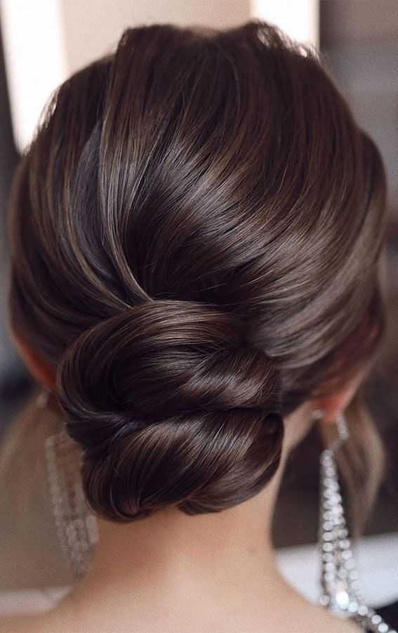 Elegant updo hairstyle with twisted bun and dangling earrings.